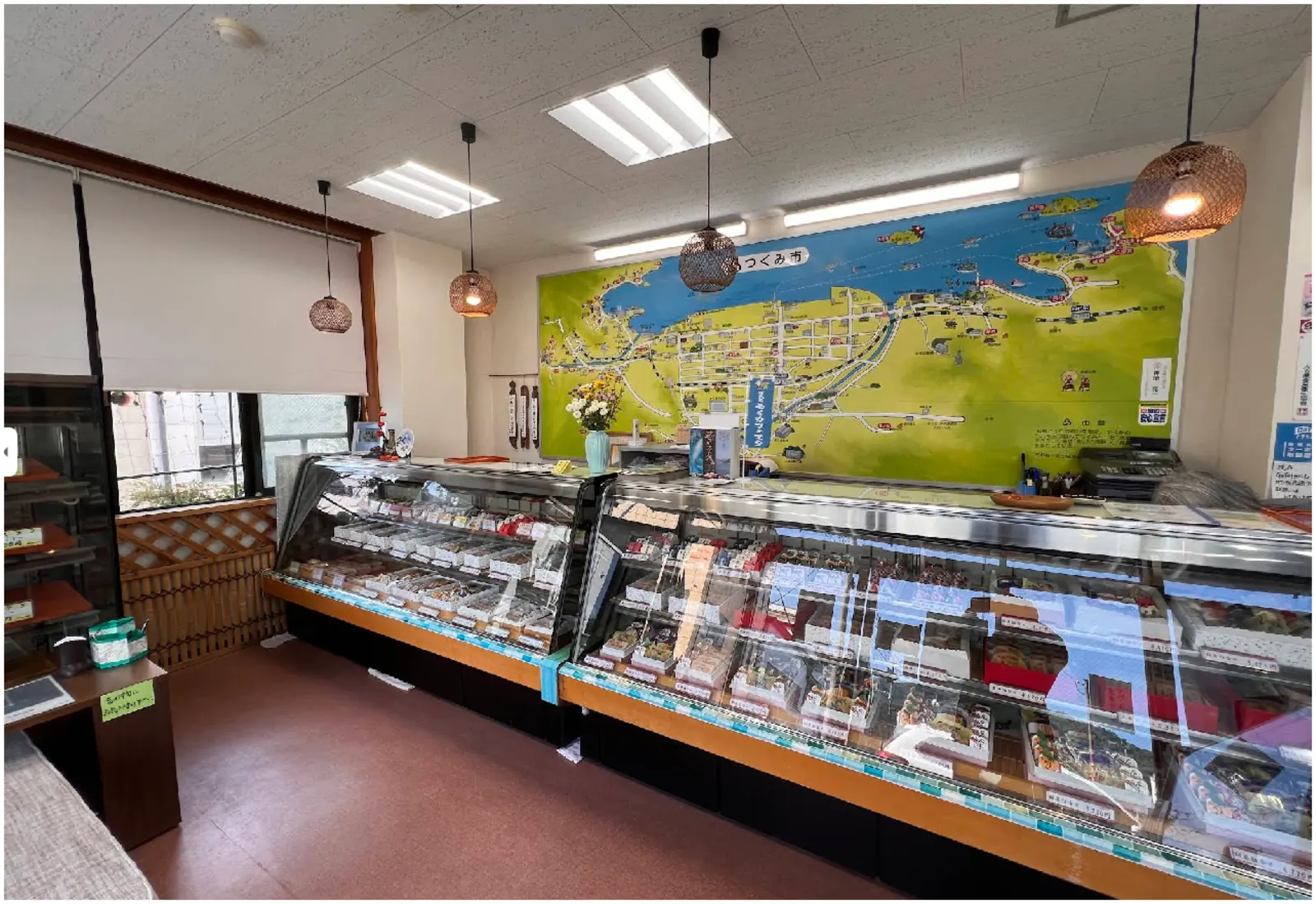 神徳菓子舗の店内。菓子の並ぶショーケースの奥に、つくみ市の絵地図が掛かる